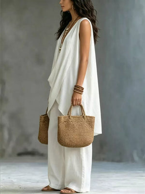 White asymmetrical sleeveless top and wide-leg pants set with a draped neckline.