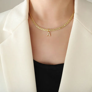 Gold initial necklace with zircon-set 'A' pendant on a textured chain.