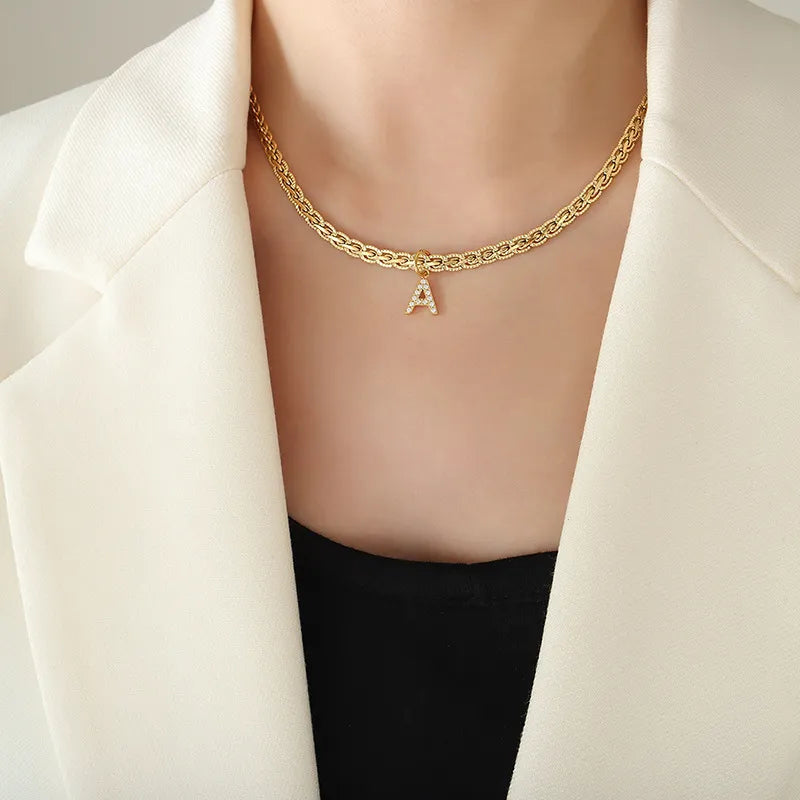 Gold initial necklace with zircon-set 'A' pendant on a textured chain.