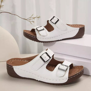 White dual buckle mid-wedge sandals with adjustable straps and brown soles.
