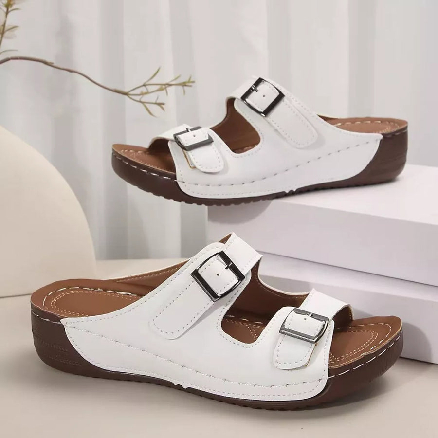 White dual buckle mid-wedge sandals with adjustable straps and brown soles.