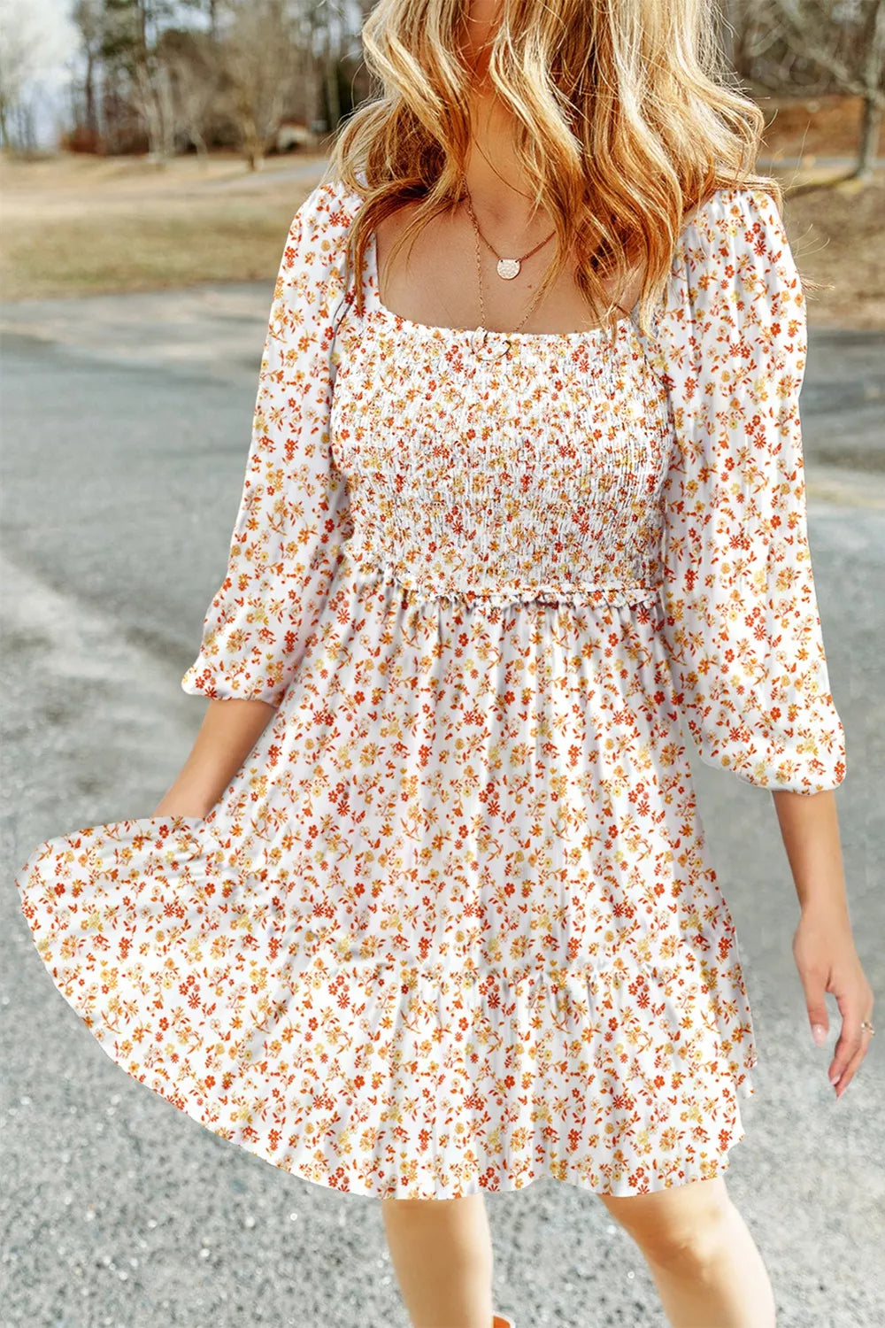 Floral smocked mini dress with square neck and puff sleeves in white with orange and yellow floral print.