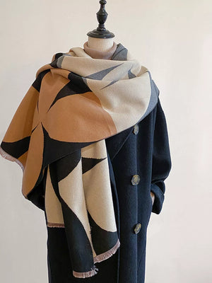 Soft geometric patterned scarf with fringes in tan, black, and cream, styled with a coat.