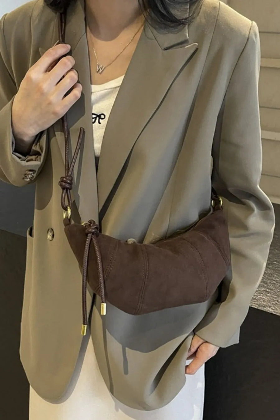 Brown crescent shoulder bag with knot detail and gold hardware
