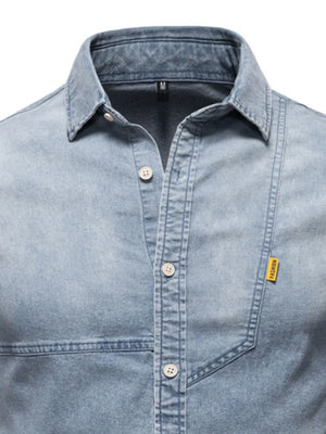 Light wash denim shirt with asymmetric pocket detail and button-down front.