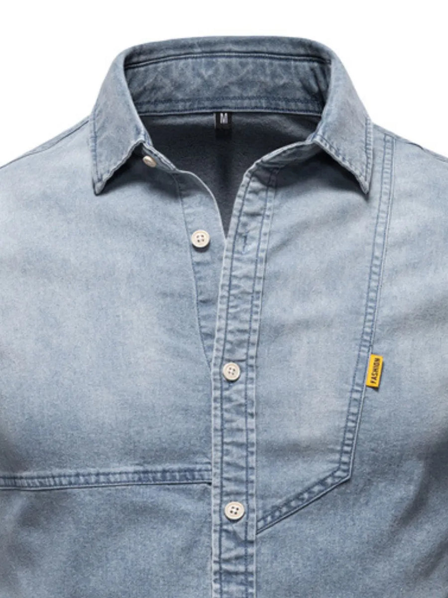 Light wash denim shirt with asymmetric pocket detail and button-down front.