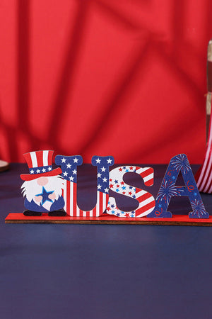 Patriotic wood block decor spelling USA with a gnome and fireworks in red, white, and blue.