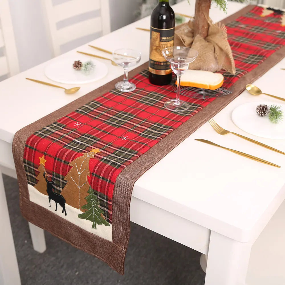Festive plaid table runner in deep red with Christmas tree and reindeer appliqué.