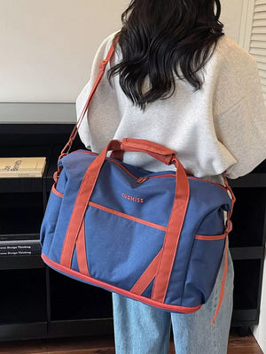 Blue duffel bag with orange trim and handles, featuring a logo.