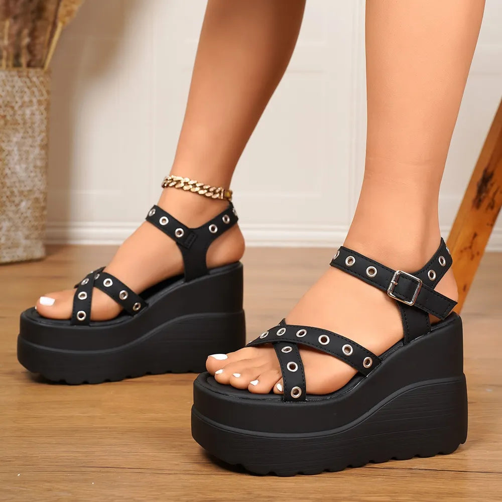 Black riveted platform wedge sandals with buckle ankle strap and crisscross toe straps.