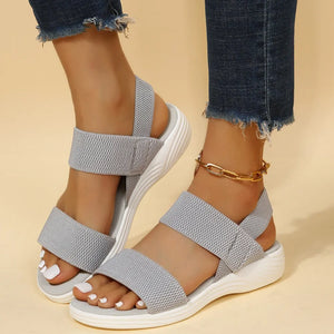 Sporty knit strap sandals in dark gray with white soles and a gold ankle bracelet.