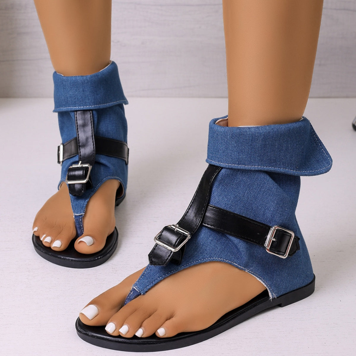 Blue denim ankle-cuff sandals with black buckle straps and a thong toe.