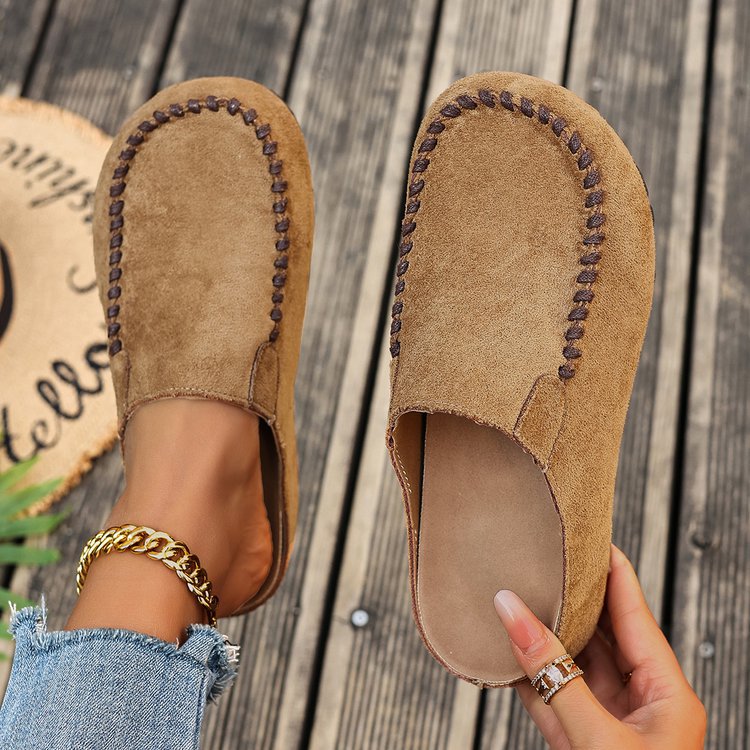 Brown suede slip-on flats with decorative stitching and a round toe.