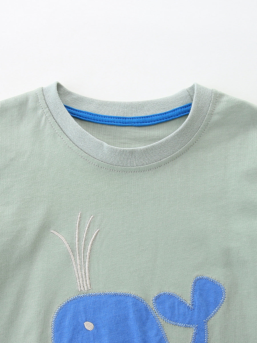 Light green cotton toddler tee with blue whale embroidery and blue neck trim.