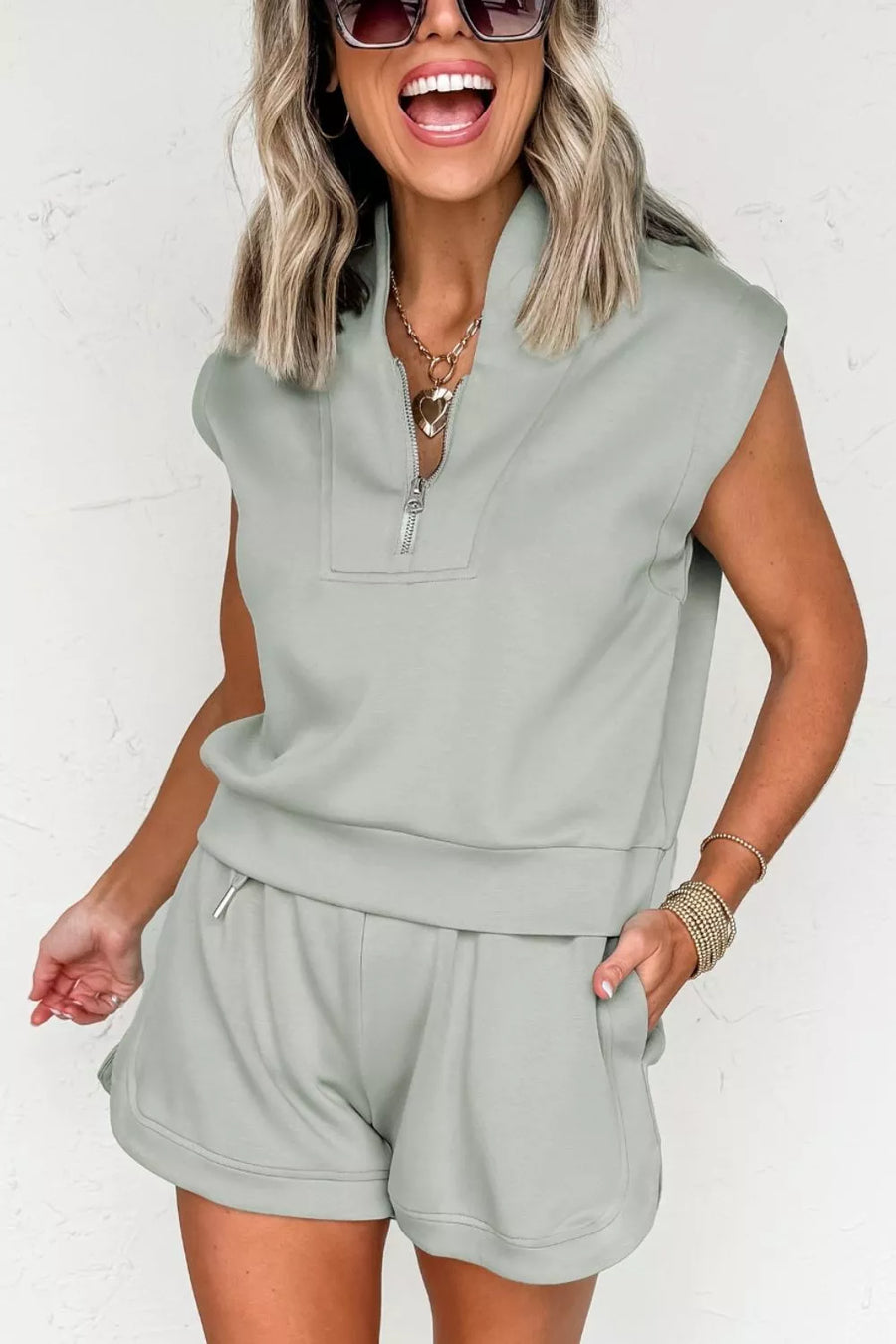 Sleek quarter-zip sleeveless top and shorts set in light green with banded hem and curved hem shorts.