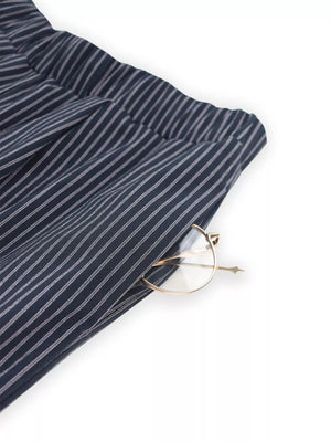 Blue striped wide-leg pants with elastic waistband and pocket detail, showing gold-rimmed glasses.