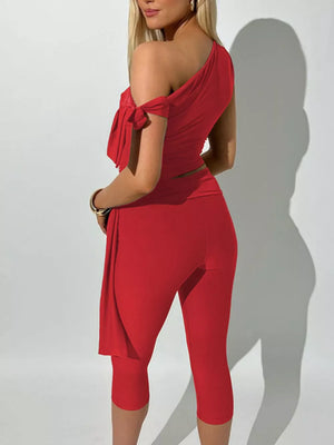 Red asymmetrical one-shoulder top with tie detail and capri pants ensemble.