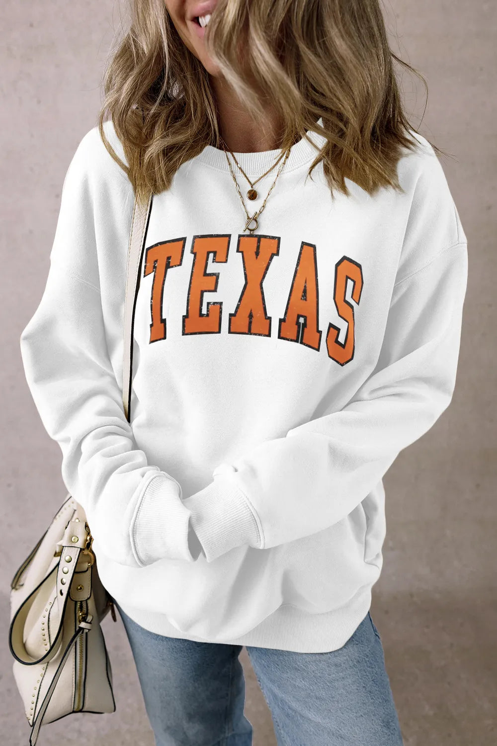 White graphic crewneck sweatshirt with orange TEXAS lettering, cotton blend.