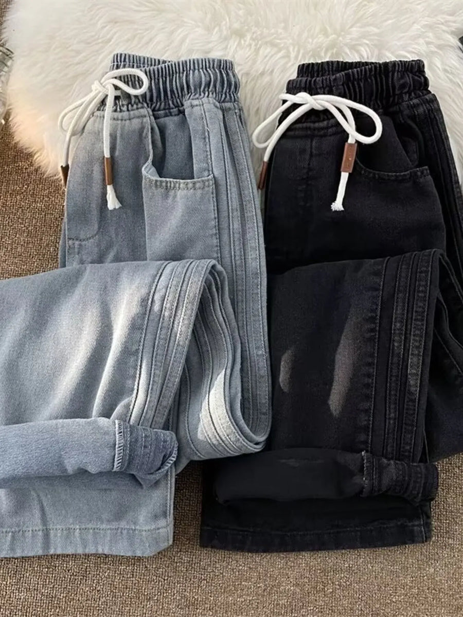 Men's wide-leg jeans in black and blue with drawstring waist and side stripe detail.