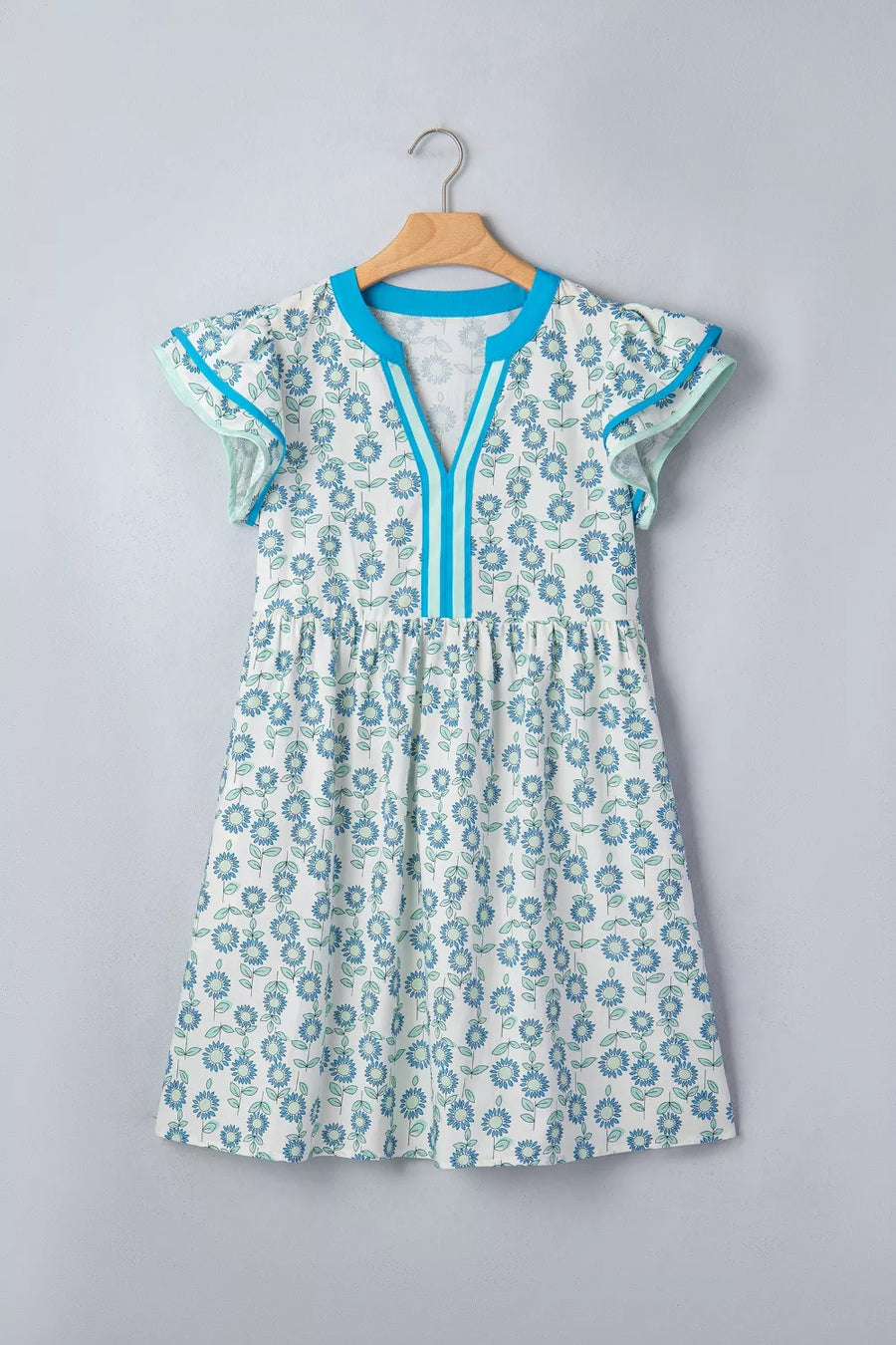 Floral print cotton blend dress with notched neckline, cap sleeves, and blue trim.