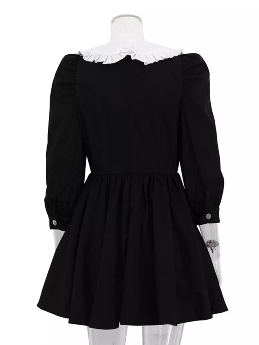 Black puff sleeve dress with a ruffled white collar and button cuffs.