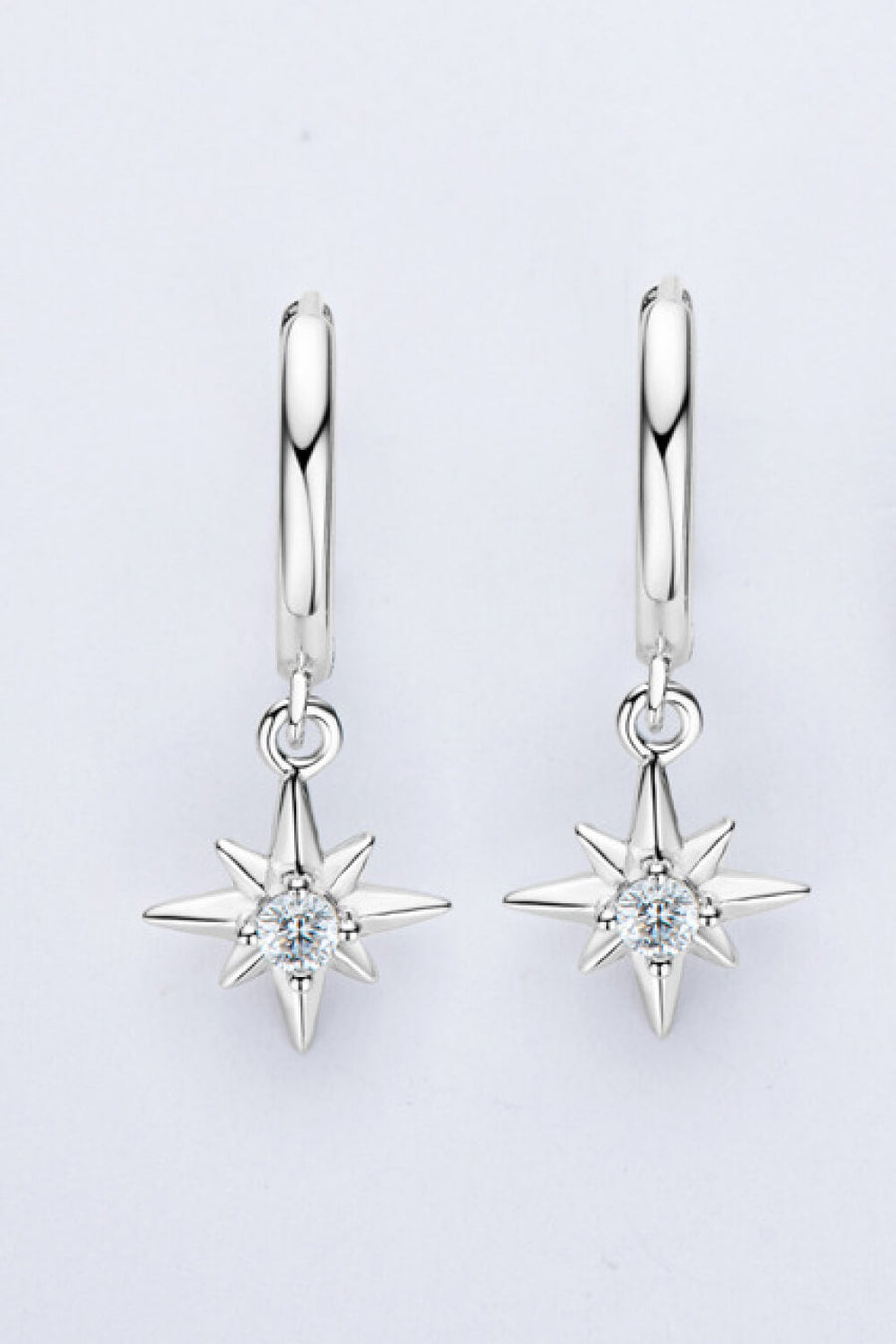 Silver hoop earrings with dangling starburst charms featuring a central crystal.