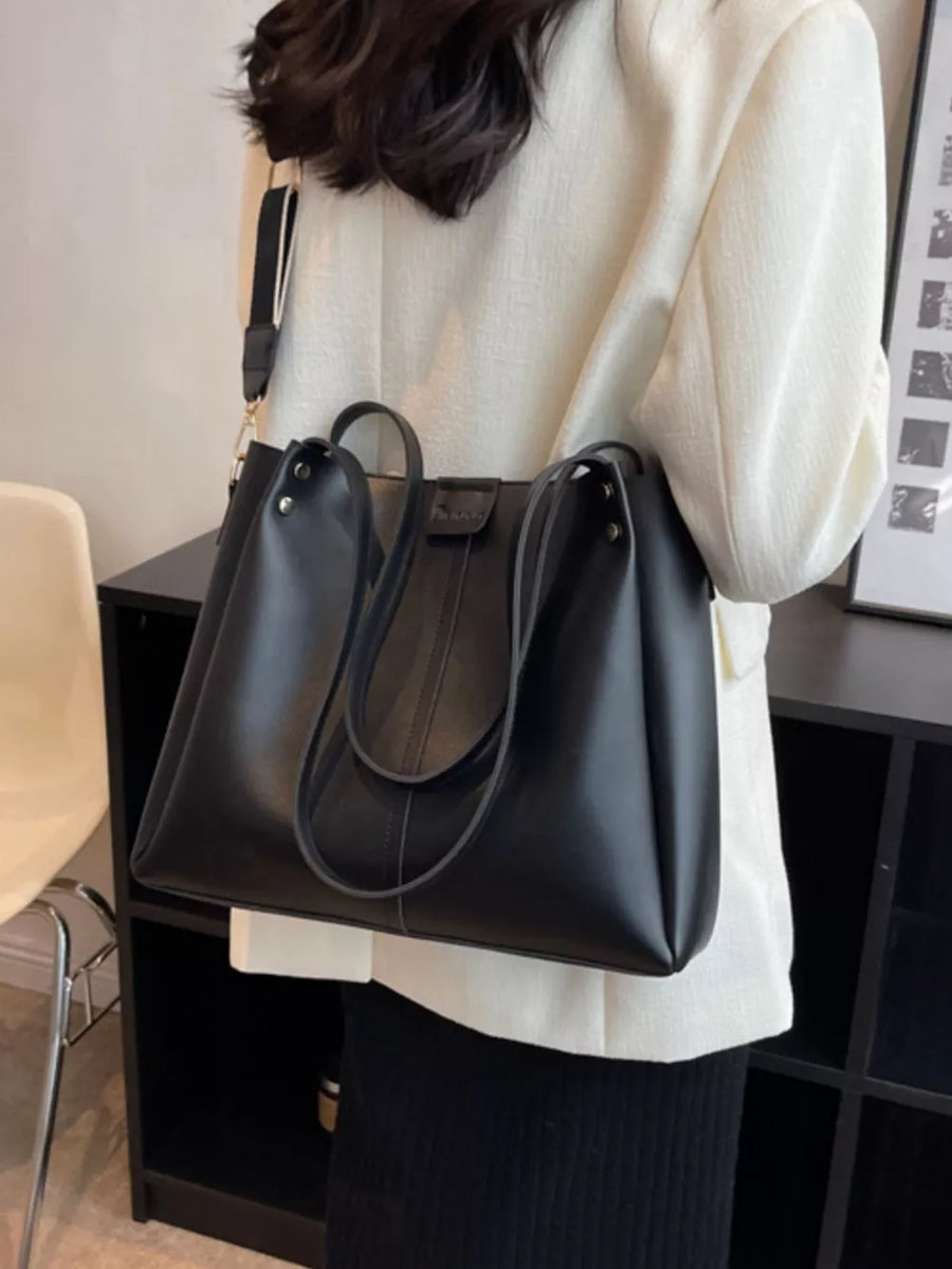 Elegant black PU leather trapezoid handbag with wide straps and detachable strap.