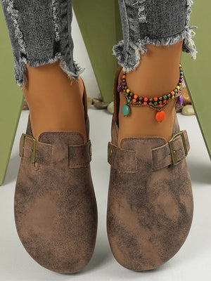 Brown textured suede mules with buckle detail and cork sole.