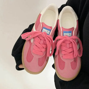 Pink suede trainers with white signature stripes and gum soles.