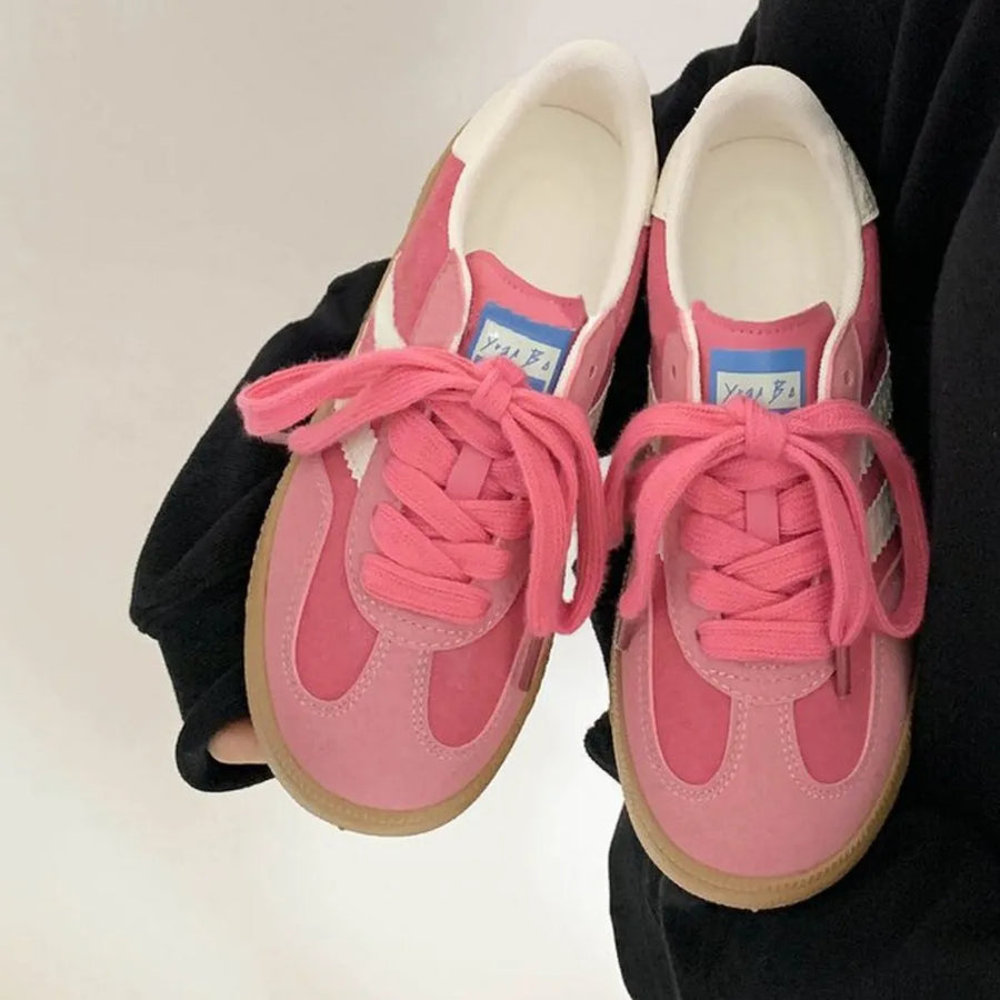 Pink suede trainers with white signature stripes and gum soles.
