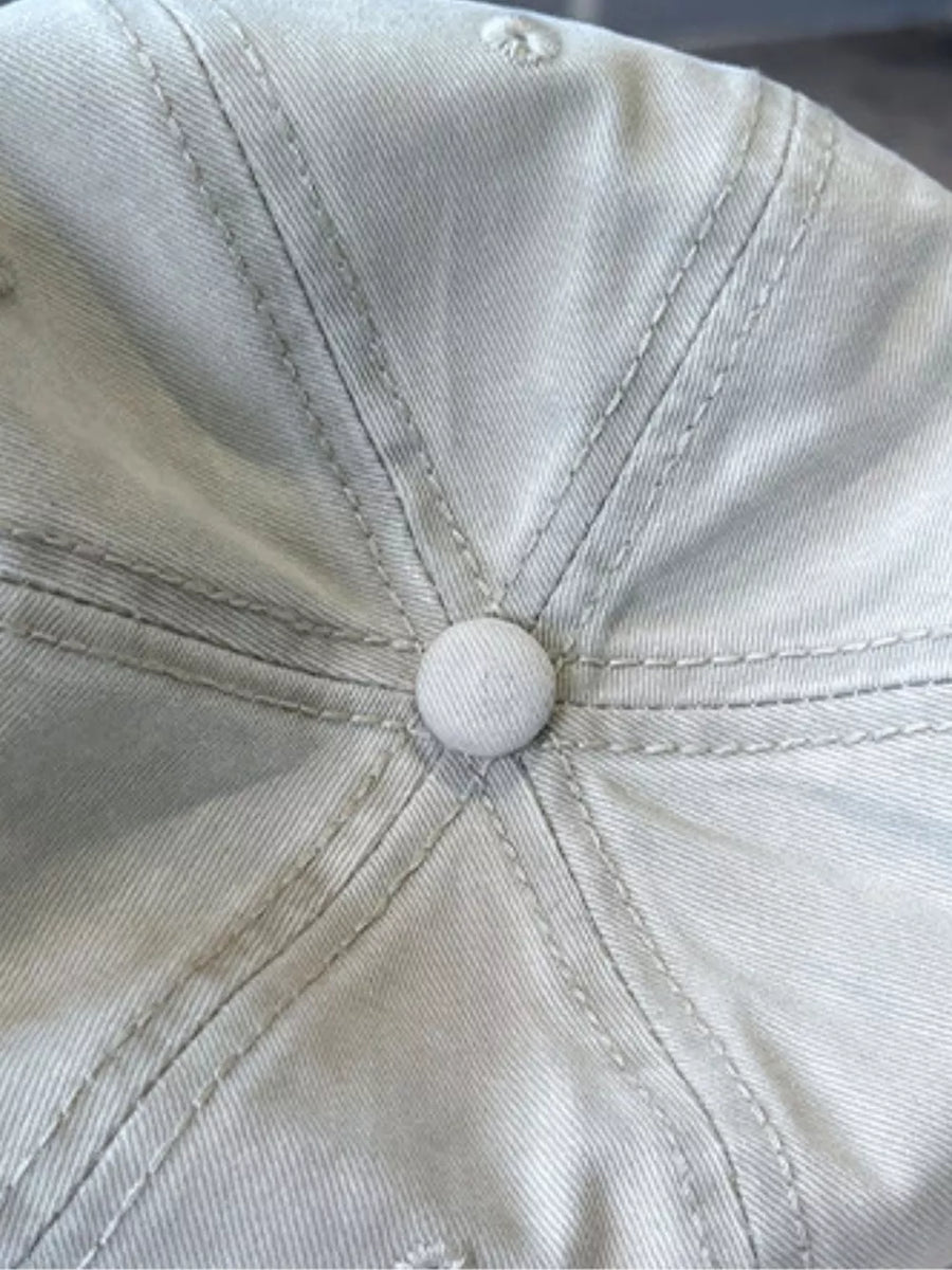 Distressed beige baseball cap with visible stitching detail and button top.