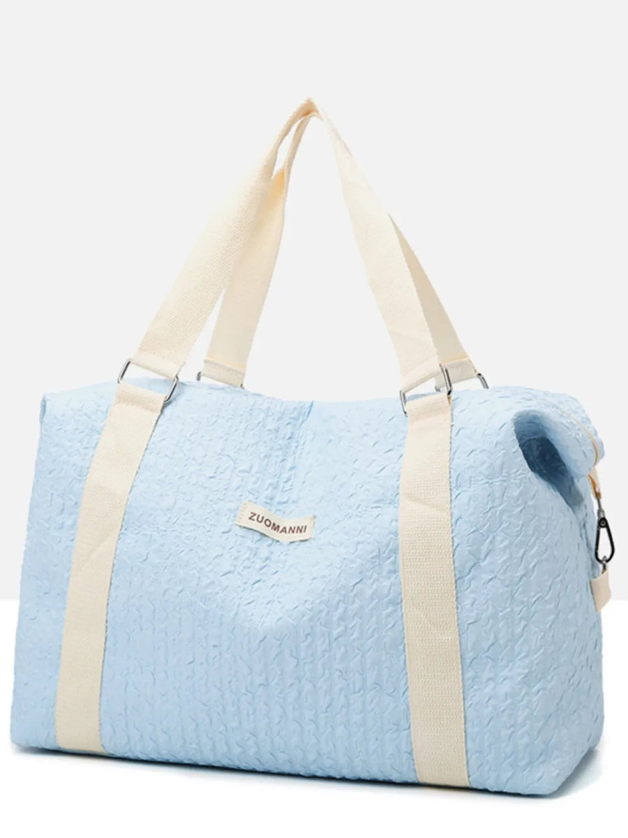 Pastel blue waffle-weave weekend bag with cream straps and silver hardware.