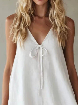 White mini dress with tie-front V-neck and spaghetti straps.