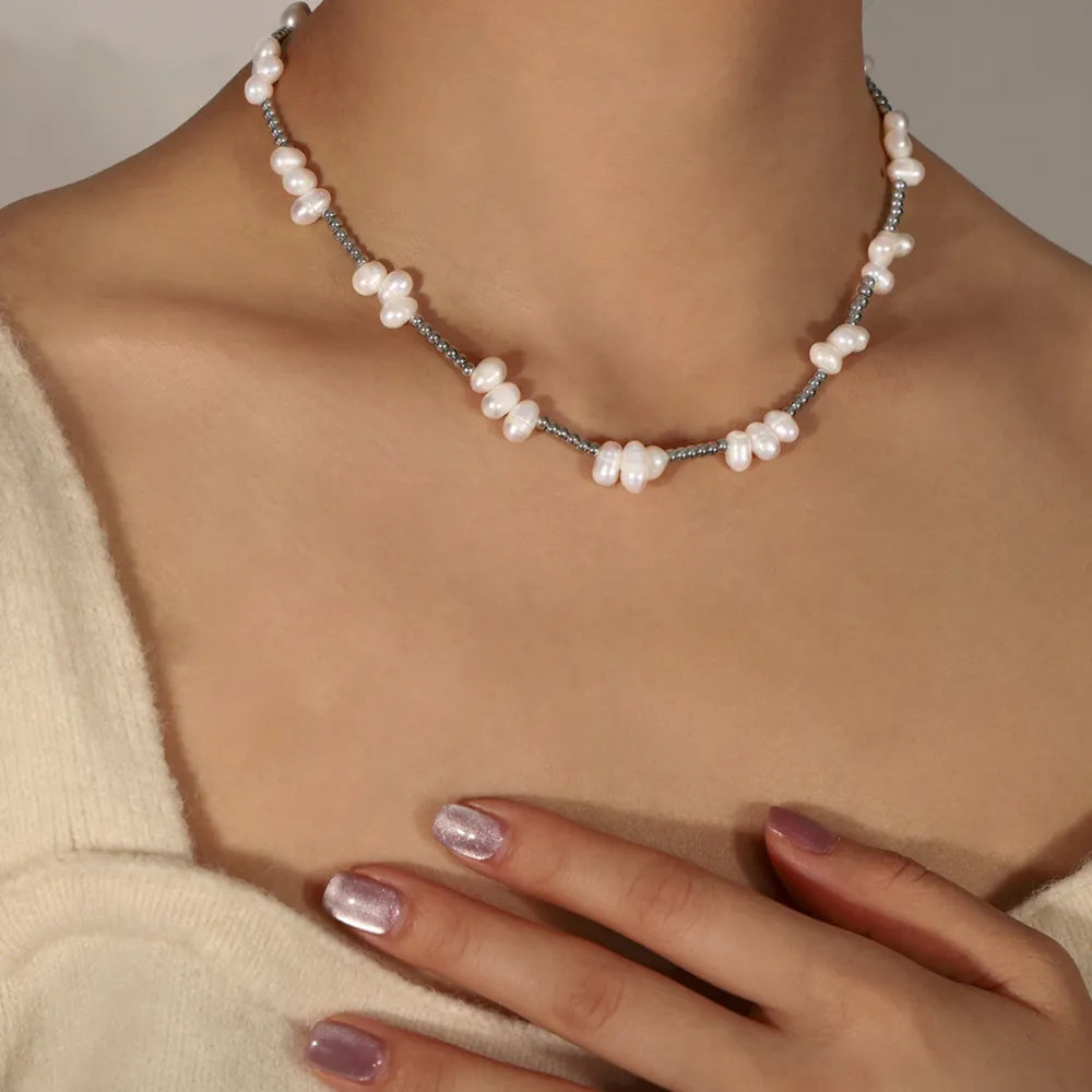 Irregular pearl cluster necklace in silver with small grey beads, styled casually on a woman.