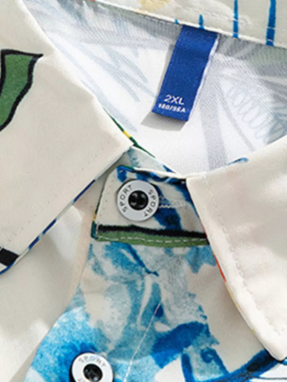 Tropical print oversized button-up shirt in white with blue floral pattern and button details.