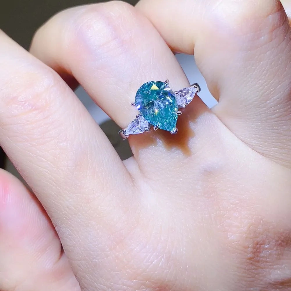 Silver ring with a large teardrop moissanite and two pear-cut side stones.