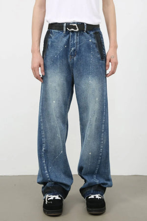 Panelled denim palazzo trousers in medium wash with paint splatters and black leather accents.