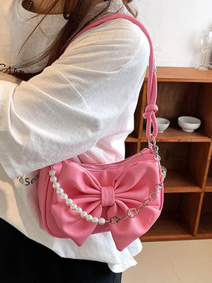 Pink shoulder bag with bowknot and pearl chain detail