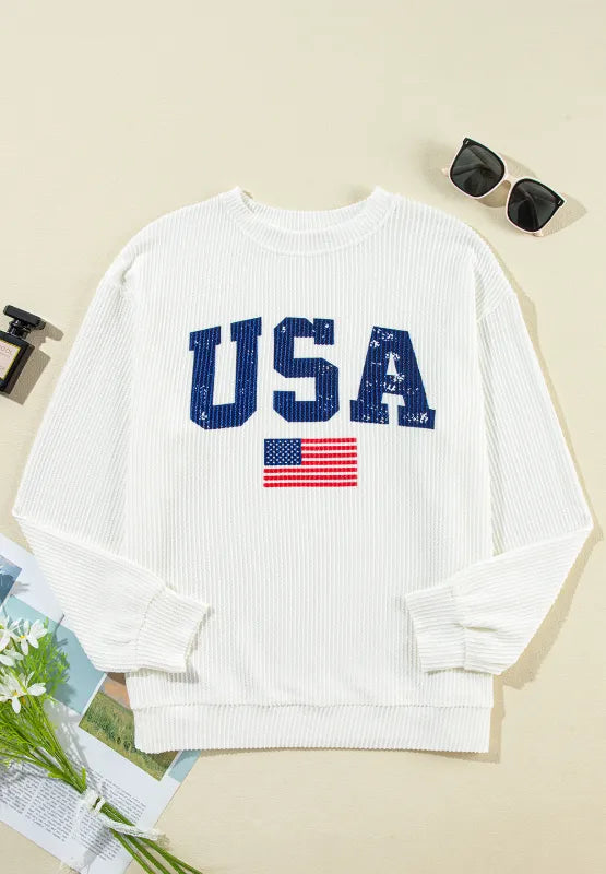 White ribbed knit sweatshirt with blue USA graphic and American flag detail.