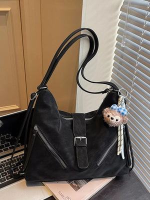 Black distressed leather buckle shoulder bag with diagonal zippers and a bear charm.