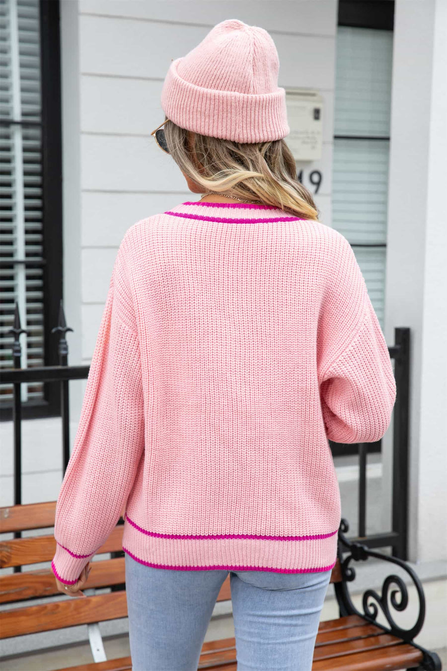 Pink acrylic cardigan with contrast trim and pockets, shown from the back.