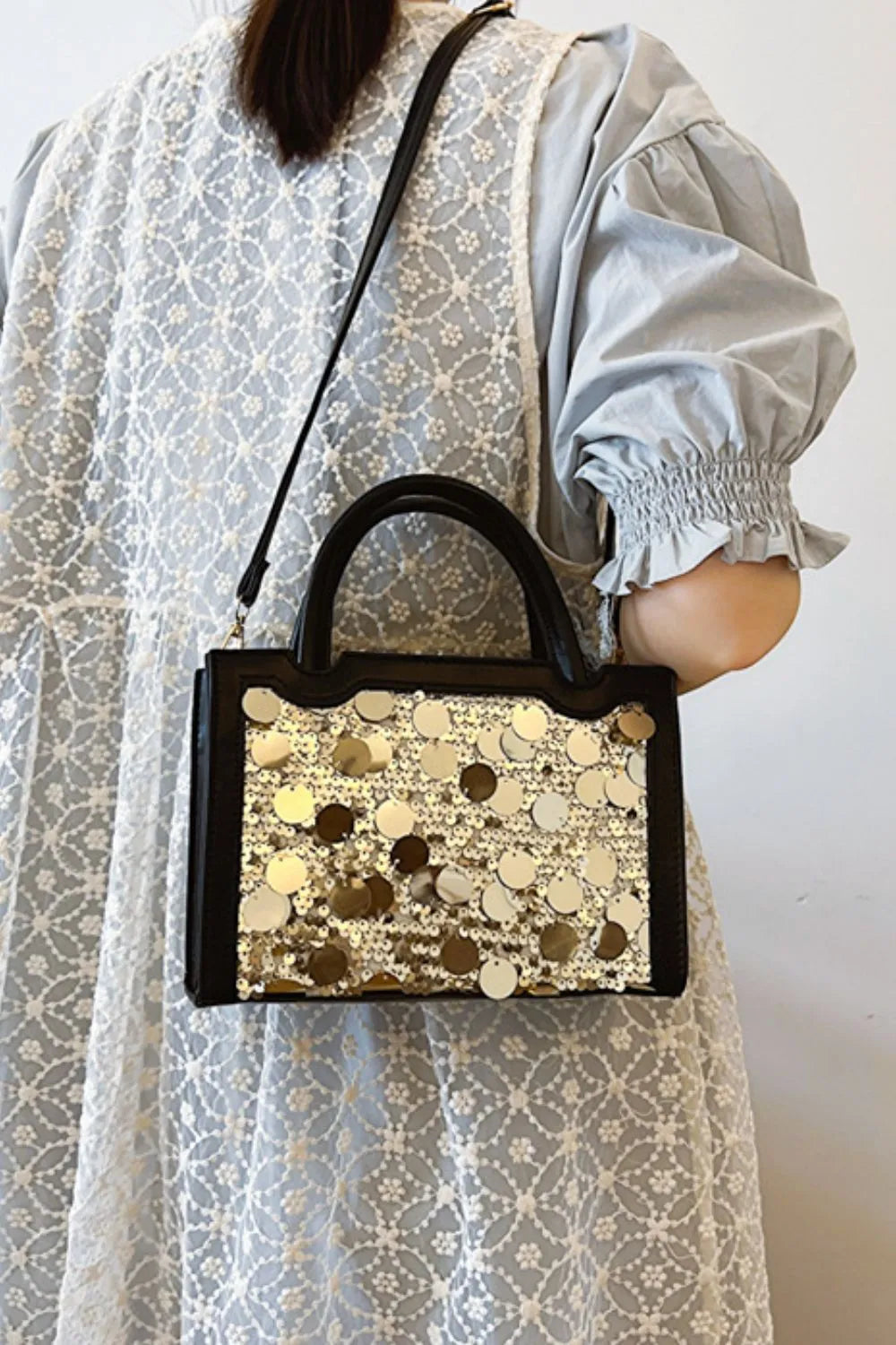 Black structured mini bag with gold sequin embellishments and top handles