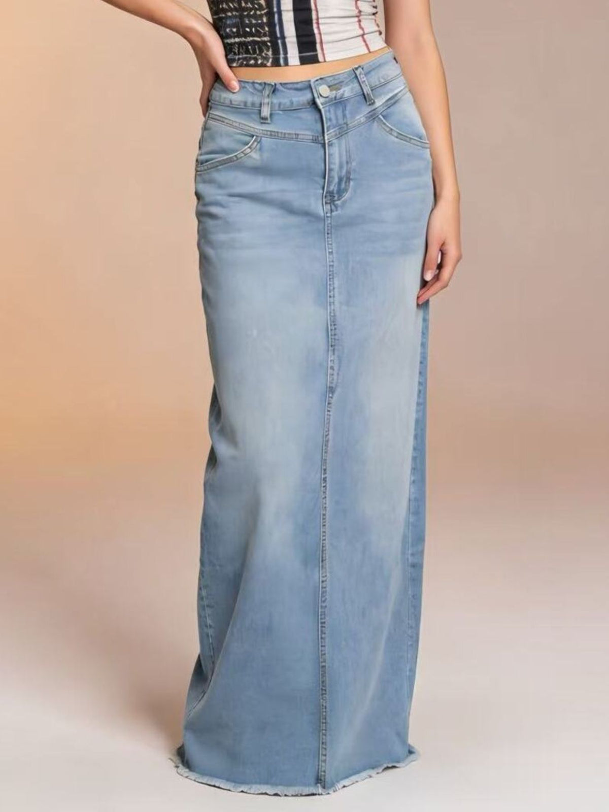 Light blue denim maxi skirt with raw hem and button closure.