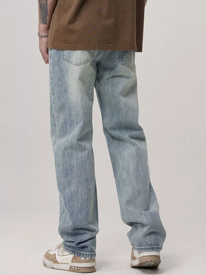 Men's light blue relaxed fit wash jeans with distressed details.