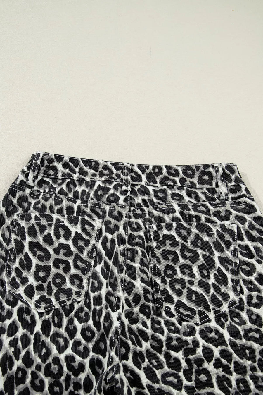 Chic cropped leopard print denim jeans with back pockets and adjustable waist detail.