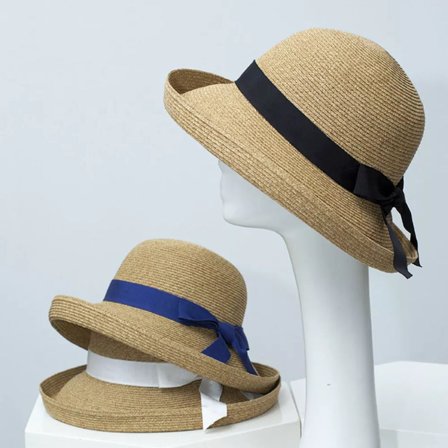 Elegant straw sun hat with black ribbon detail and bow, bell-shaped brim.