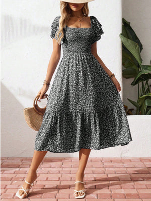Black floral smocked dress with ruffle sleeves, square neckline, and tiered skirt.