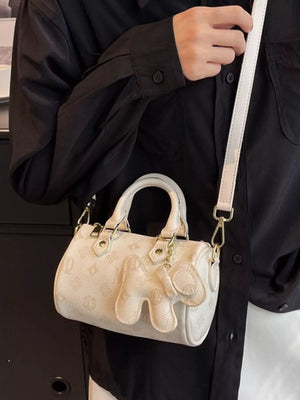 White mini barrel crossbody bag with allover monogram pattern and elephant charm