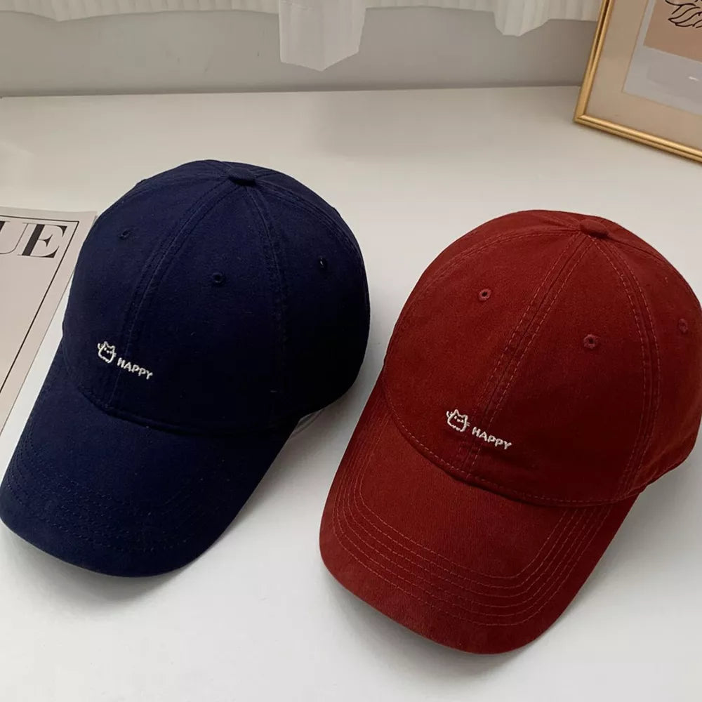 Navy and wine red cotton baseball hats with embroidered cat and happy graphic.