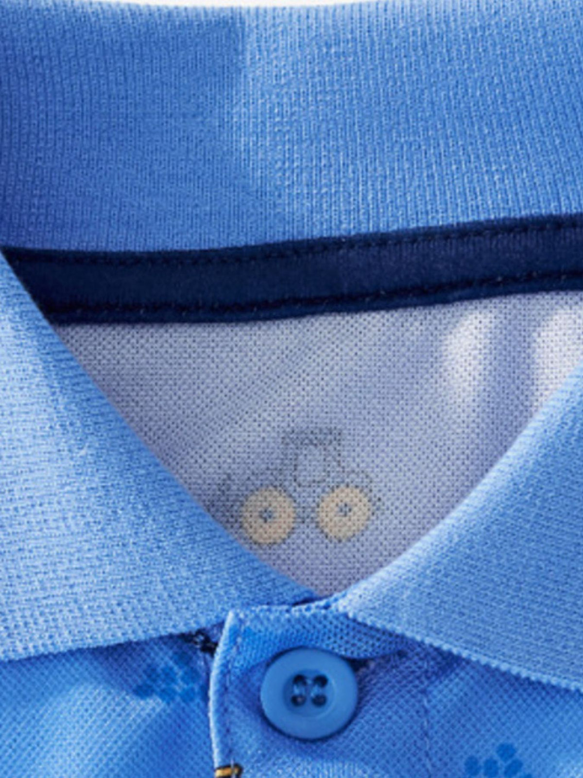 Toddler blue polo shirt with excavator print, navy collar trim, and button closure.
